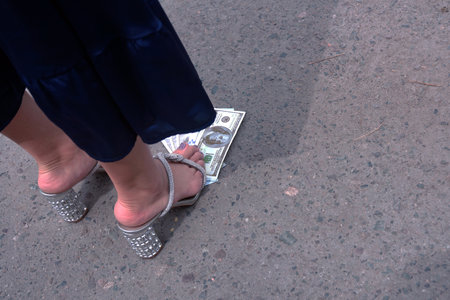 An elegant women's shoe stands on paper banknotes of the American dollar.の写真素材