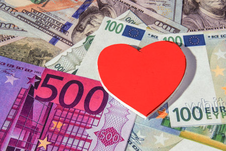 A symbol of family difficulties in life. Red, white heart over American and European money.の写真素材