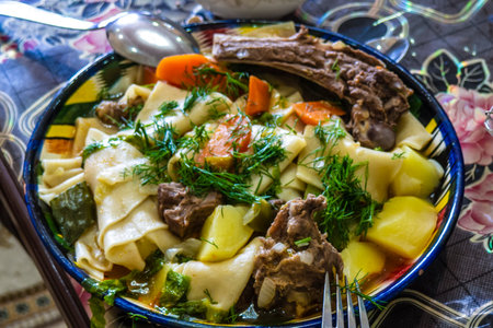 Homemade lamb beshbarmak served with vegetables and fresh herbs. A delicious traditional Central Asian meal symbolizing hospitality and family.の写真素材