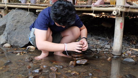young man sort stone in the river の写真素材