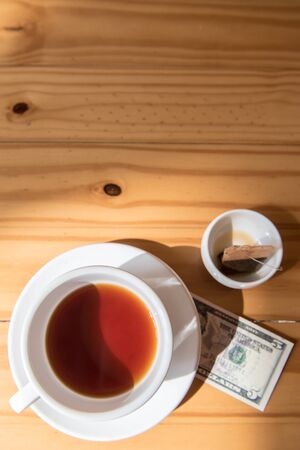make money tip dollar or euro for travel and tea cup near on the wooden tableの写真素材