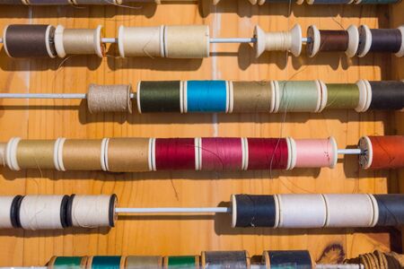 Colorful thread spools show on wooden table close up. Sewing string, handicraft conceptの写真素材