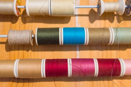 Colorful thread spools show on wooden table close up. Sewing string, handicraft conceptの写真素材