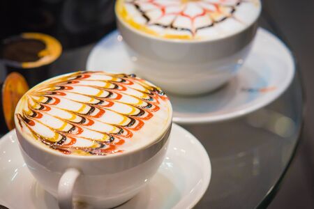 The Late arts coffee. Coffee arts.  Two hot coffee set in a white cup on desk or table の写真素材