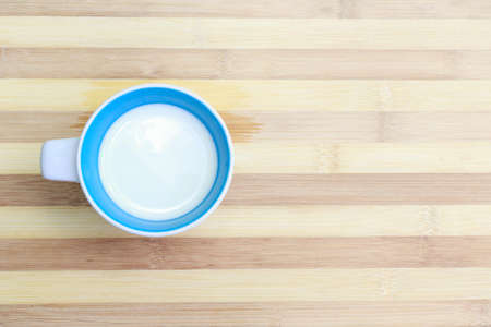 Milk in a glass on a wooden table top viewの写真素材