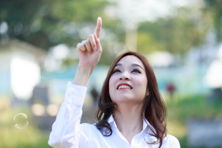 Beautiful Asian women is pointing at something in a parkの写真素材