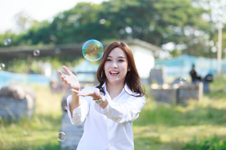 Pretty Asian women playing happily bubbles in the park.の写真素材
