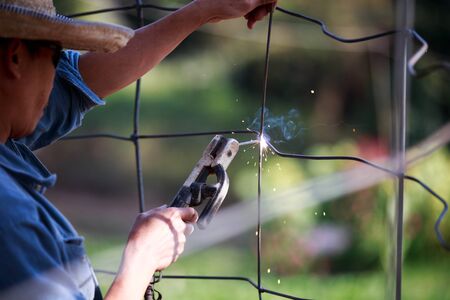 Man using welding metal cage fence.