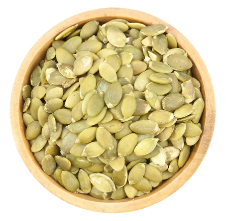 Pumpkin Seeds  in a wood bowl  isolated on white backgroundの写真素材