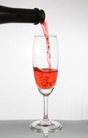red wine pouring into a glass isolated on white backgroundの写真素材