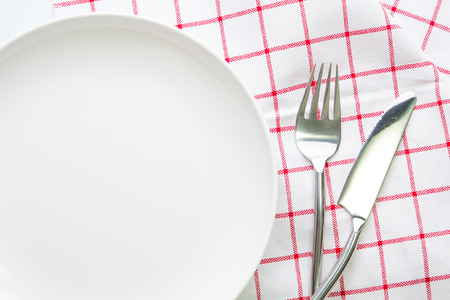 knife white plate and fork spoon on red checked tableclothの写真素材