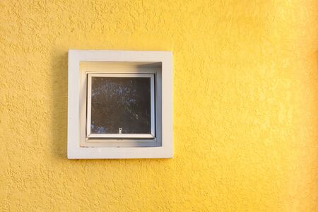 Yellow rough grunge concrete wall with a ventilation windowの写真素材