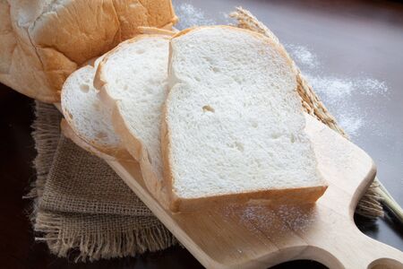 Bread with wheat ears on dark board with flour