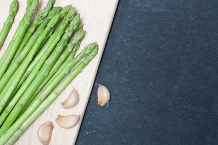 bunch of asparagus over chopping wood on slate backgroundの写真素材