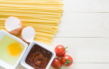 spaghetti with ingredients for cooking on woodの写真素材