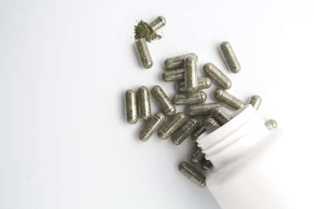 herb capsule from bottle on white backgroundの写真素材