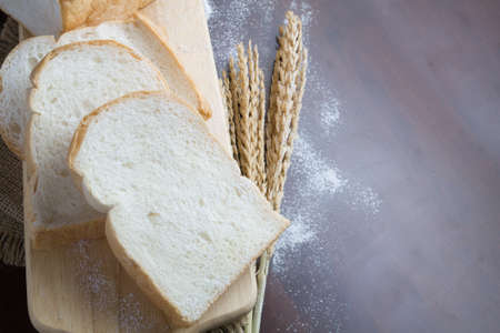 Bread with wheat ears on dark board with flour