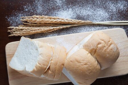 Bread with wheat ears on dark board with flour