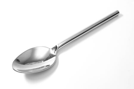 Stainless steel glossy metal kitchen spoon isolated over the white backgroundの写真素材