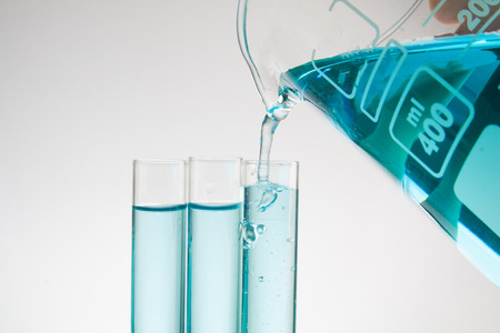 Science pipette with a pour of substance over laboratory test tubes