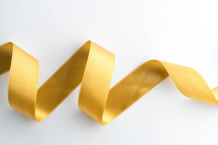 gold bow ribbon satin texture isolated on white backgroundの写真素材