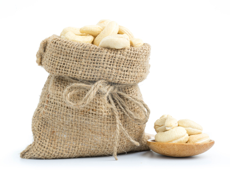 Cashew nuts in burlap sack isolated on white backgroundの写真素材