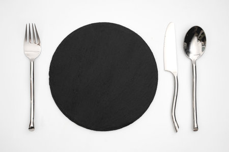 empty black stone plate spoon fork knife on white