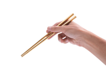 Gold chopsticks in hand on white backgroundの写真素材