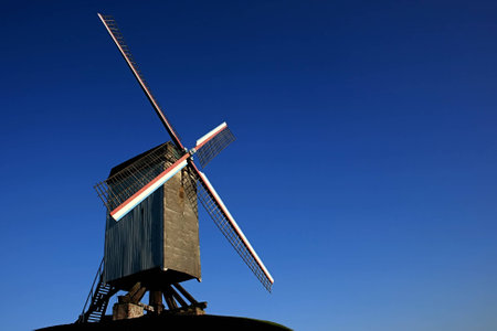 Old vintage windmill under the clear blue sky in Bruges, Belgiumの写真素材