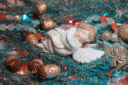Christmas background with fir branches and Christmas toys. Angel sleeping on spruce branches. Tonal stylization in retro style.の写真素材