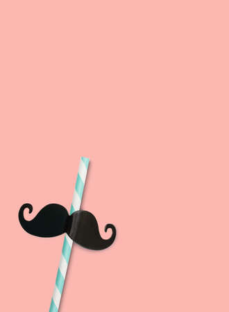 A paper cocktail tube decorated with a black mustache on a pink background.の写真素材