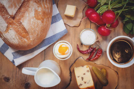 Continental breakfast with black coffee and milk on old wooden tableの写真素材