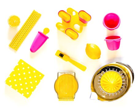 Pink and yellow kitchen utensils on a white tableの写真素材