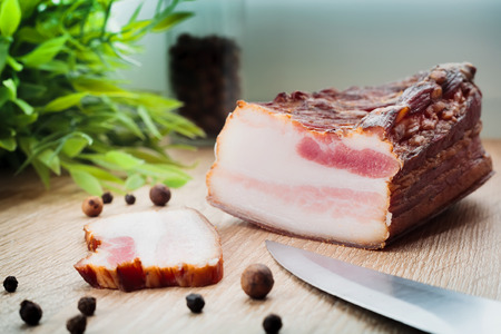 Fresh homemade smoked bacon on a wooden plateの写真素材