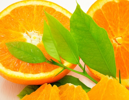 Half orange, orange slices and green leaves