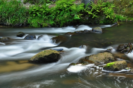 A small river flows through a wild landscape with rocksの写真素材
