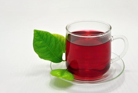 Glass cup of hot fruit tea and green lemon leafの写真素材