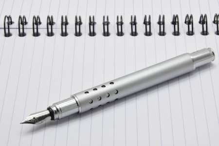 Metal ink pen and notepad with black spiralの写真素材