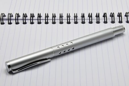 Metal ink pen and notepad with black spiralの写真素材