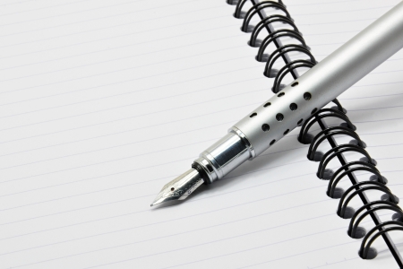 Metal ink pen and notepad with black spiralの写真素材