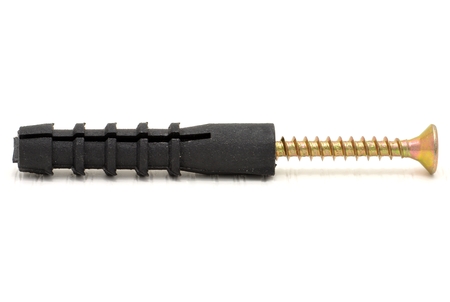 Golden screw and black dowel on a white backgroundの写真素材