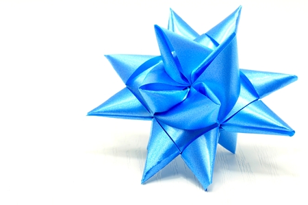Christmas star made of blue ribbons on white の写真素材