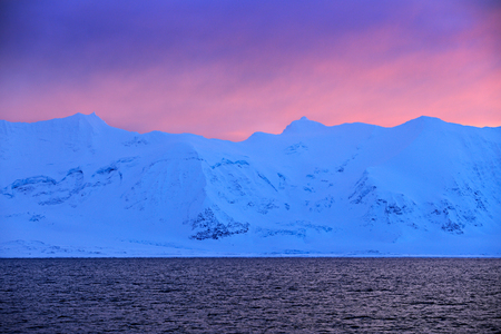 Winter Arctic. White snowy mountain, blue glacier Svalbard, Norway. Ice in ocean. Iceberg twilight in North pole. Pink clouds with ice floe. Beautiful landscape. Land of ice. Night ocean with ice.の写真素材