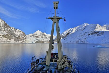 Boat in winter Arctic. White snowy mountain, blue glacier Svalbard, Norway. Ice in ocean. Iceberg twilight in North pole. Pink clouds, ice floe. Travel in Arctic. Ship and land of ice.の写真素材