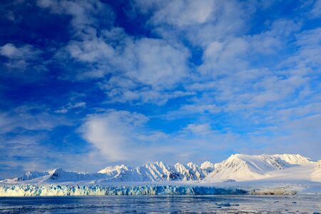 White snowy mountain, blue glacier Svalbard, Norway. Ice in ocean. Iceberg in North pole. Blue sky with ice floe. Beautiful landscape. Cold sea  water. Land of ice. Traveling in Arctic Norway.の写真素材