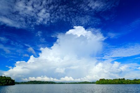 Storm clouds with dark blue sky. Bentota Ganga river, Sri Lanka. Summer landscape with white stormy...