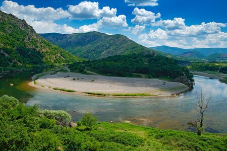 Valley of Arda river near Madzarovo, Bulgaria, Eastern Rhodopes. Summer day in Bulgaria. River Landscape with green hills. Traveling Balkan, Europe. Water, blue sky, white clouds. Mountains, Europe.の写真素材