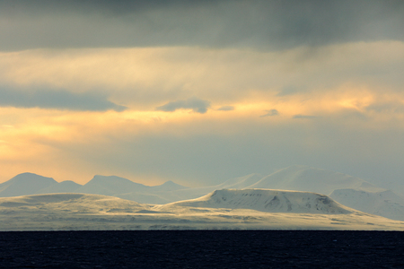 White snowy mountain, blue glacier Svalbard, Norway. Ice in ocean. Iceberg twilight in North pole. Pink clouds with ice floe. Beautiful landscape. Land of ice. Cold blue water. Evening with sea ice.の写真素材