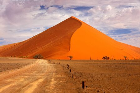 Namibia landscape. Big orange dune with blue sky and clouds, Sossusvlei, Namib desert, Namibia, Southern Africa. Red sand, biggest dune in the world. Travelling in Africa.の写真素材