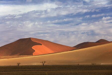 Namibia landscape. Big orange dune with blue sky and clouds, Sossusvlei, Namib desert, Namibia, Southern Africa. Red sand, biggest dune in the world. Travelling in Africa.の写真素材